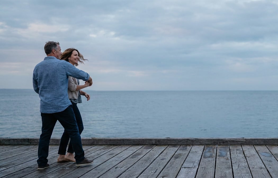 Two people dancing together on a seaside pier